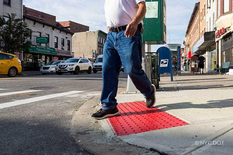 Pedestrian walking at crosswalk with ramp with red DWS